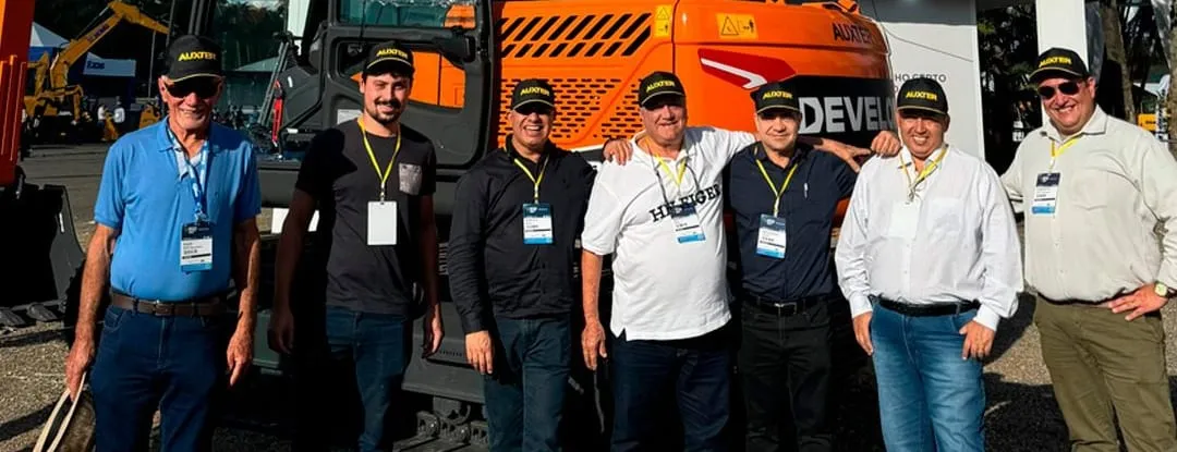 Equipe da Auxter reunida em frente a maquinas durante um evento do setor